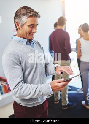 Enjoying the benefits of cloud computing. a mature businessman using a digital tablet in an office setting. Stock Photo
