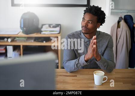 Dreaming up new designs. a young male designer deep in thought while sitting at his desk in on office. Stock Photo