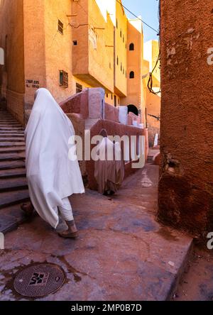 Mozabite women in white haïk in the streets of Ksar El Atteuf, North Africa, Ghardaia, Algeria Stock Photo