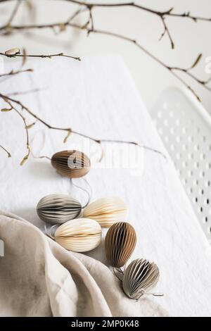 Easter paper pastel colored eggs on white linen tablecloth. Scandinavian-style Easter decorations. Stock Photo