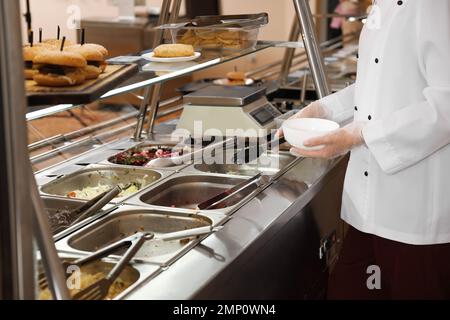 School canteen worker at serving line, closeup. Tasty food Stock Photo