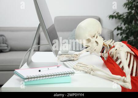 Human skeleton in red dress using computer at home Stock Photo