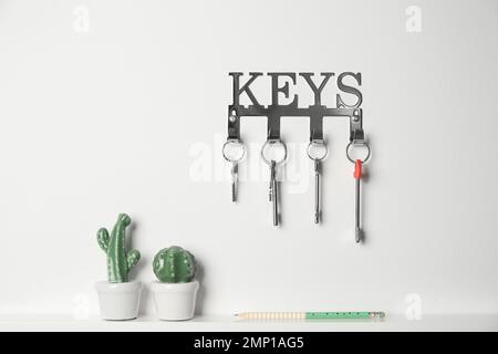 Metal key holder on light wall indoors Stock Photo