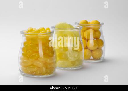 Different tasty lemon drops in jars isolated on white Stock Photo