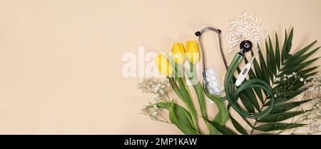 Bouquet of flowers and stethoscope on a beige background, a place for text, happy doctors day, nurses week and other medical holidays. Stock Photo