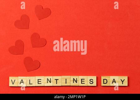 Hearts, inscription made of wooden cubes of Valentine's Day on a red background with a copy of the picture, top view.Concept for Valentine's Day Stock Photo