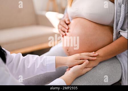 Cropped image of a female doctor reassuring and comforting a pregnant woman by touching or holding her hand. motherhood, pregnancy medical checkup con Stock Photo