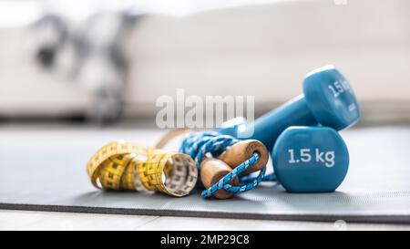 Jump rope and tape measure on the mat at home in the living room. Concept of healthy lifestyle. Stock Photo