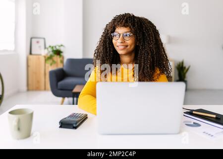 African american freelance woman working on laptop sitting on table at home Stock Photo