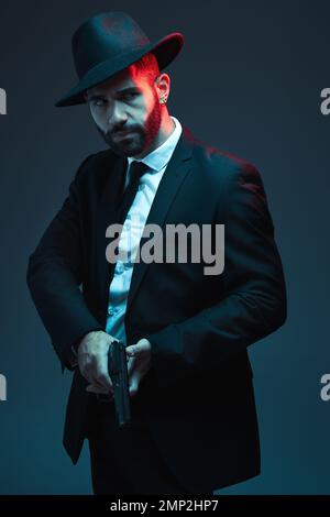 Man, suit or holding gun on dark studio background in secret spy, isolated mafia leadership or crime lord security. Model, gangster or hitman with Stock Photo