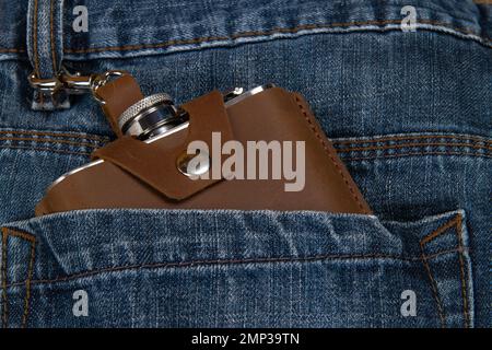 Hip flask in full grain leather case in denim blue jeans pocket Stock Photo