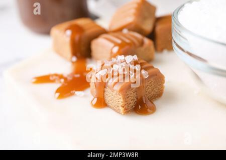 Salted caramel with sauce on white board, closeup view Stock Photo