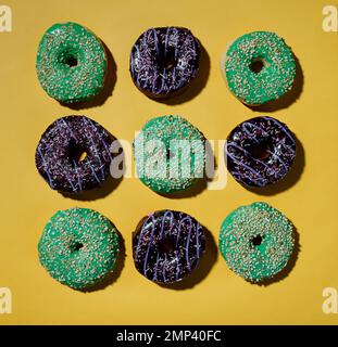 Multicolored donuts pattern on yellow background. Hard shadows. Flat lay. Top view Stock Photo