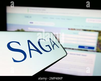 Smartphone with logo of travel and financial services company Saga plc on screen in front of website. Focus on center-left of phone display. Stock Photo