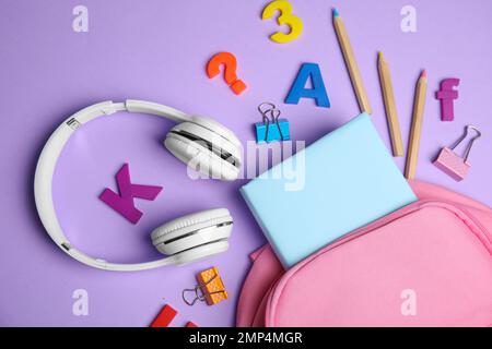 Flat lay composition with book and headphones on lilac background Stock Photo