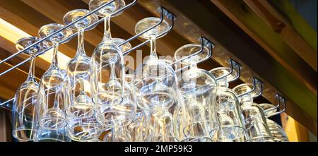 clean wine glasses hang over the bar. Glass, utensils, objects. Stock Photo