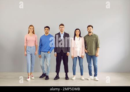 Group portrait of five serious young people in smart casual clothes standing in studio Stock Photo