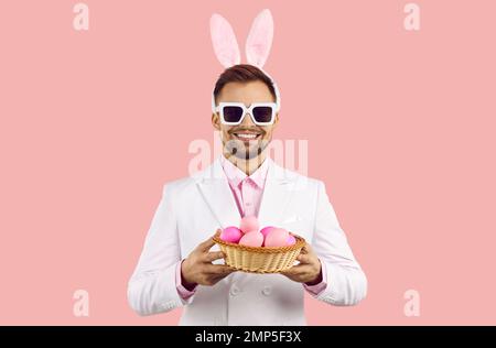 Smiling man with bunny ears hold basket with eggs Stock Photo