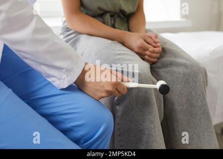 Neurologist examining child patient and using medical hammer to check knee reflex Stock Photo