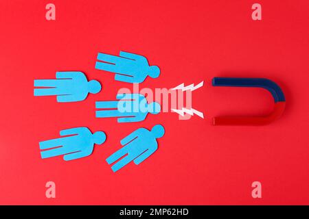 Magnet and paper people on red background, flat lay Stock Photo