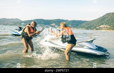 Senior happy couple having playful fun at jet ski on beach island hopping tour - Active elderly travel concept around the world with retired people Stock Photo