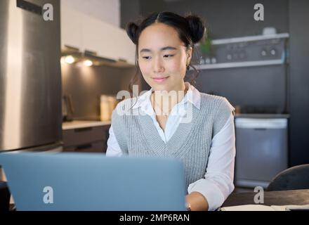 Remote work, laptop and freelancer woman is working at her home typing growth strategy or project online. Employee, worker or Asian consultant doing Stock Photo