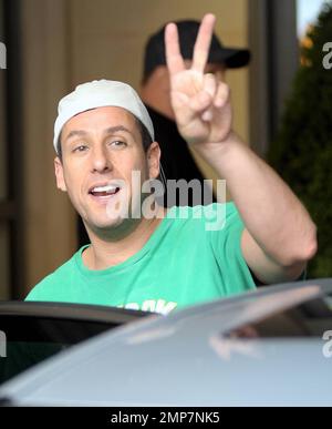 Adam Sandler flashes a peace sign as he leaves his luxury hotel with