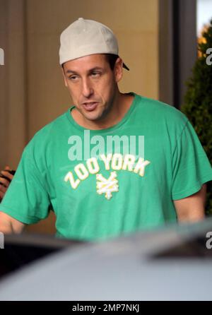 Adam Sandler flashes a peace sign as he leaves his luxury hotel with