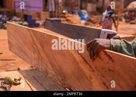 Close up of a carpenter's hands cutting a plank with the hand saw Stock Photo