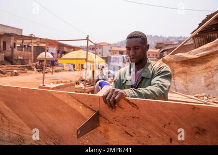 A carpenter cuts a board with a hand saw in his workshop in Africa. Stock Photo
