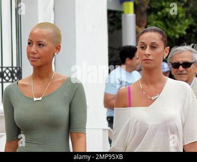 EXCLUSIVE!! Amber Rose spends the day with her girlfriends in South Beach taking in the sights of Ocean Drive. Without her boyfriend Kanye West in sight, Amber Rose made waves amongst the men on the popular beachside street as she wiggled her way through the crowds in a pair of high heels and a micro-mini dress that showed off her curves. One male even dropped his drink as she walked by his table. Amber and one of girlfriends were wearing matching gold and diamond name necklaces. The model stopped a couple of times along the way to greet admirers before going for lunch. Miami, FL. 11/7/09. Stock Photo