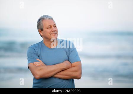 Cheerful retired man with crossed arms by the sea Stock Photo