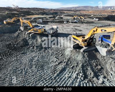 Excavators working together on huge mining site, Caterpillar excavators Stock Photo