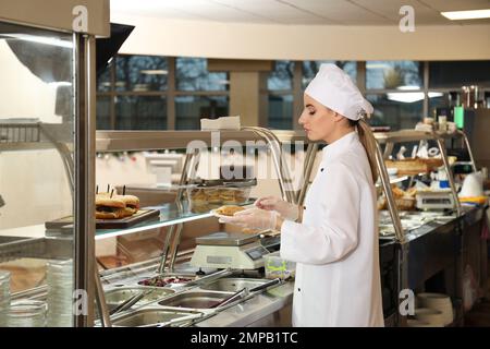 School canteen worker at serving line. Tasty food Stock Photo