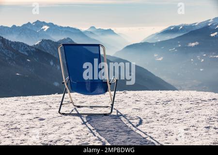 Sunbeds with a view of the Pinzolo valley. Inversion and fog over the ski area of Pinzolo (TN) Italy. A view from above of a fog-covered valley. Super Stock Photo