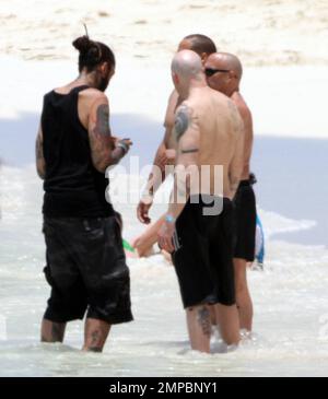 EXCLUSIVE!! Avril Lavigne shows off her fit figure in a black and white bikini during a beach break with her band and her brother, Matt Lavigne, at the Atlantis Paradise Island Resort ahead of her concert. Avril relaxed in a beachside cabana with a group of people including fellow artist Travie McCoy and took a dip in the ocean wearing a hat. Avril, who is still sporting her blonde and green hairstyle following her recent Asian tour, was happy to pose for photos for a member of her group to commemorate the moment over Memorial Weekend. Paradise Island, Bahamas. 5/27/11. Stock Photo