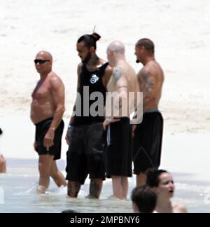 EXCLUSIVE!! Avril Lavigne shows off her fit figure in a black and white bikini during a beach break with her band and her brother, Matt Lavigne, at the Atlantis Paradise Island Resort ahead of her concert. Avril relaxed in a beachside cabana with a group of people including fellow artist Travie McCoy and took a dip in the ocean wearing a hat. Avril, who is still sporting her blonde and green hairstyle following her recent Asian tour, was happy to pose for photos for a member of her group to commemorate the moment over Memorial Weekend. Paradise Island, Bahamas. 5/27/11. Stock Photo