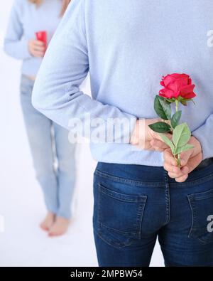 Young attractive man holding a rose behind his back to surprise his lover. Stock Photo