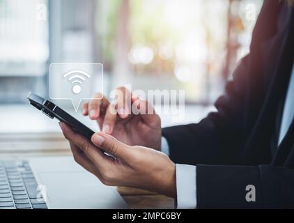 Share wifi by smart mobile phone. Sharing icon appear on cell phone holding by business people in suit, sharing wifi connection for working with lapto Stock Photo
