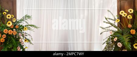 Empty white thin rectangle frame on white soft curtain background decoration with yellow and orange color flowers and green leaves on vintage wooden d Stock Photo