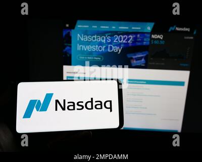 Person holding smartphone with logo of US stock exchange Nasdaq on screen in front of website. Focus on phone display. Stock Photo