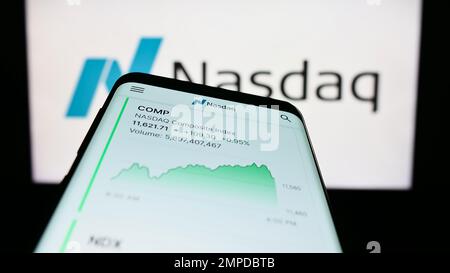 Smartphone with website of US stock exchange Nasdaq on screen in front of business logo. Focus on top-left of phone display. Stock Photo