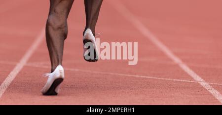African-american male sportsman running on stadium track, dynamic run of sprinter in a stadium Stock Photo