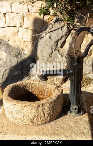 An old water pump with water coming from it, at the La Ermita Vella d Olta church in Spain Stock Photo