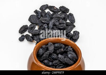 Black Raisins in Bowl, Heap Of Black Raisins, Isolated On White Background Stock Photo