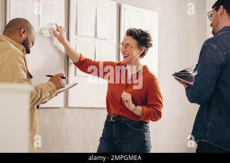 Cheerful businesswoman laughing happily while having a discussion with her team. Group of diverse businesspeople working on a new marketing strategy i Stock Photo