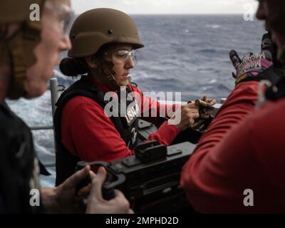 221019-N-IL330-1291 PHILIPPINE SEA (Oct 19, 2022) – Aviation Ordnanceman 2nd Class Kayla Garcia, from Lamar, Colorado, feeds ammunition to an M2HB .50-caliber machine gun during a crew-served weapons qualification aboard amphibious assault carrier USS Tripoli (LHA 7) Oct. 19, 2022. Tripoli is operating in the U.S. 7th Fleet area of operations to enhance interoperability with allies and partners and serve as a ready response force to defend peace and maintain stability in the Indo-Pacific region. Stock Photo