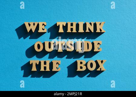 We Think Outside The Box, words in wooden alphabet letters isolated on blue background Stock Photo