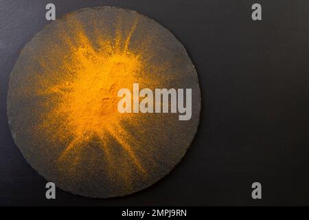 Orange curry powder explosion on black stone texture, soft focus close up Stock Photo