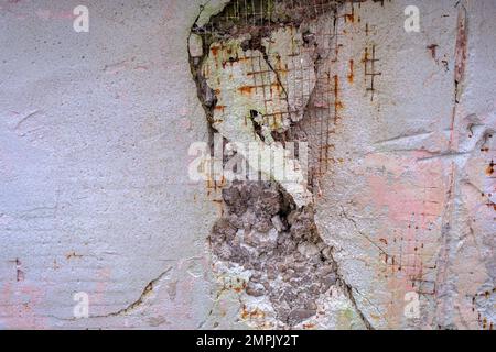 Rough concrete wall background with rusty wire rebar. Damaged wall background. Stock Photo